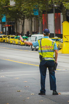 Policeman in australia, Melbourne is controlling traffic. Back view of an australian traffic police stopping cars with his hand.