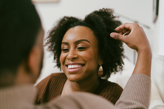 Intimate coversation, black couple at home, man plays with hair, affectionately