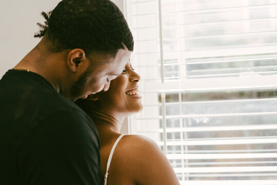 Happy, affectionate African American couple hugging in kitchen