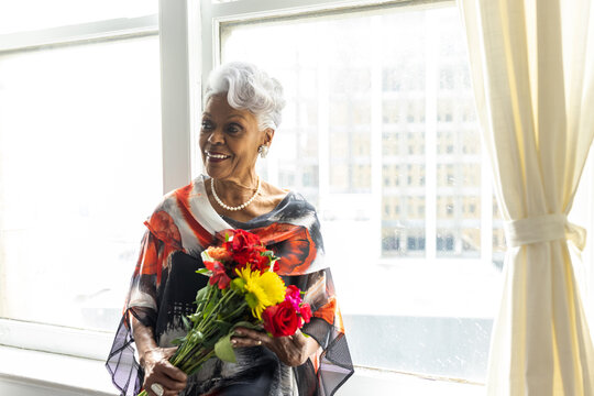 Portrait of pretty senior Black woman holding flowers, love
