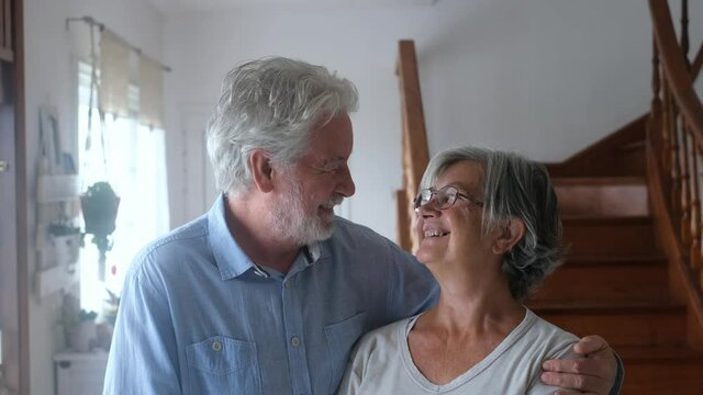 Portrait of couple of two happy and healthy seniors old people smiling and looking at the camera. Close up of mature grandparents enjoying and having fun together at home indoor.
