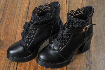 Woman high hills boot with lace on a wooden floor. High fashion industry. Leather stylish shoes