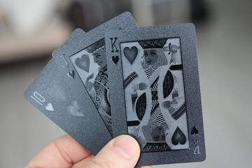 Male hand holds black playing cards closeup