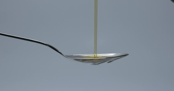 Slow motion of pouring olive oil on spoon