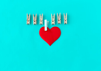 love symbol, heart with a white clothespin and other clothespins on a turquoise background