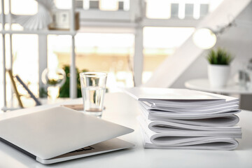 Stack of blank magazines and laptop on table