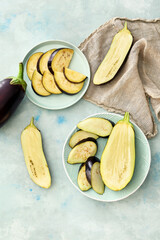 Plates with sliced eggplants on light background