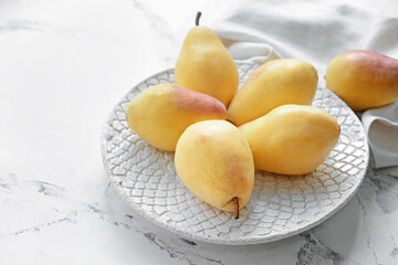 Plate with fresh pears on light background
