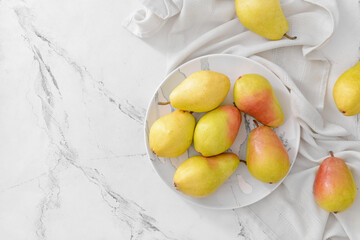 Plate with fresh pears on light background