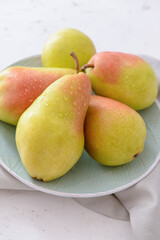 Plate with fresh pears on light background
