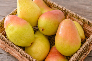 Basket with fresh pears on wooden background