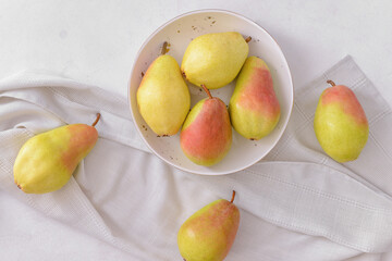Plate with fresh pears on light background