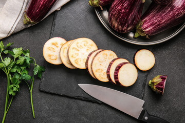 Board with chopped eggplant on dark background