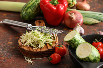 Fresh vegetables and grater on grunge background