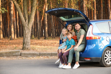 Happy family sitting in car trunk outdoors