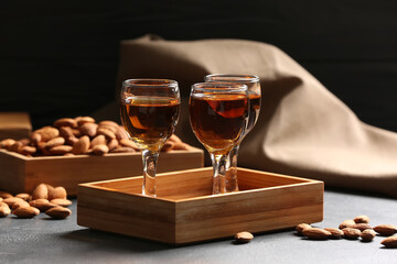 Tray with glasses of almond liquor and nuts on dark background