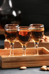 Tray with glasses of almond liquor and nuts on dark background