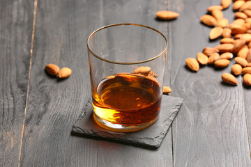 Glass of almond liquor and nuts on dark wooden background