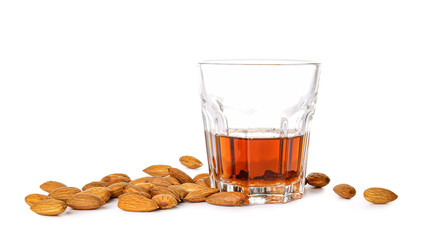 Glass of almond liquor and nuts on white background