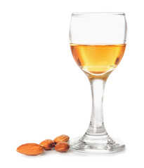 Glass of almond liquor and nuts on white background