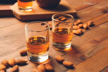 Glasses of almond liquor and nuts on wooden background