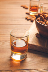 Glasses of almond liquor and nuts on wooden background