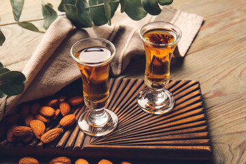 Glasses of almond liquor and nuts on wooden background