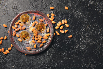 Tray with glasses of almond liquor and nuts on dark background