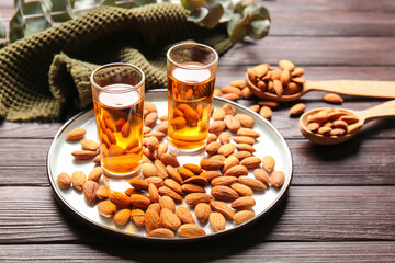 Tray with glasses of almond liquor and nuts on wooden background