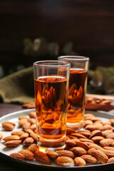 Tray with glasses of almond liquor and nuts on dark background, closeup