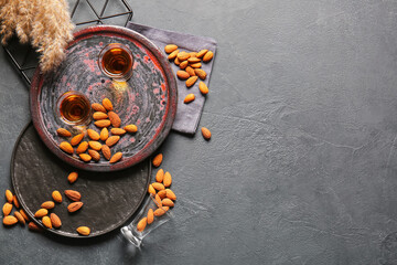 Tray with glasses of almond liquor and nuts on dark background