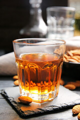 Glass of almond liquor and nuts on dark background, closeup