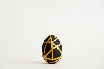 Easter golden egg with geometric black pattern isolated on white background. Minimal easter concept. Happy Easter card with copy space for text. Top view, flatlay. Concept for banner, flyer