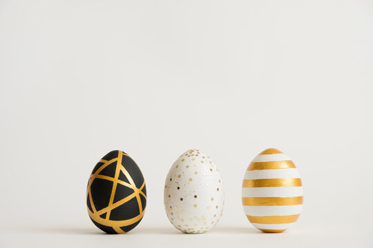 Three Easter golden decorated eggs isolated on white background. Minimal easter concept. Happy Easter card with copy space for text. Top view, flatlay.