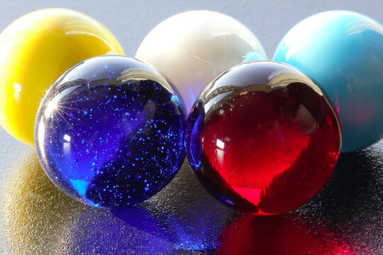 5: Marbles with 5: colours on black table top- stock photo