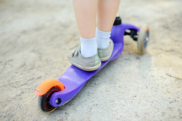 Toddler baby learning to ride kick scooter. Child feet close up. Sport lifestyle and leisure for kids.