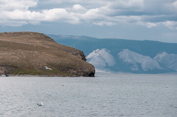 View of Lake Baikal in Siberia with a cape, cloudy sky and seagulls