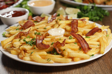 Portion of french fries with bacon. Lettuce, green onion, tomato, ketchup and mayonnaise