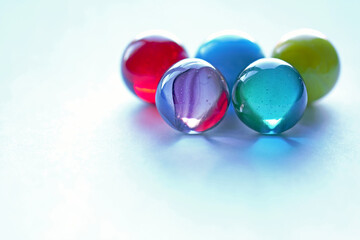 5 Large multi-coloured marbles on white surface Top Left - stock photo