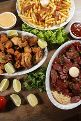 Portion of pepperoni sausage with lemon, fries, bacon and fried chicken. Lettuce, potato, green onion, ketchup and mayonnaise