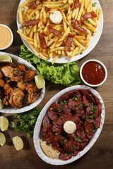 Portion of pepperoni sausage with lemon, fries, bacon and fried chicken. Lettuce, potato, green onion, ketchup and mayonnaise