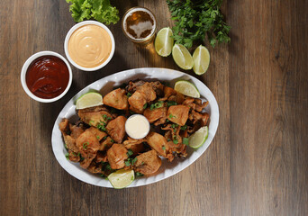 Portion of fried chicken with lemon. Lettuce, green onion, ketchup and mayonnaise