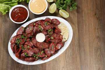 Portion of pepperoni sausage with lemon. Lettuce, green onion, ketchup and mayonnaise