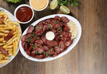 Portion of pepperoni sausage with lemon. Lettuce, green onion, ketchup and mayonnaise