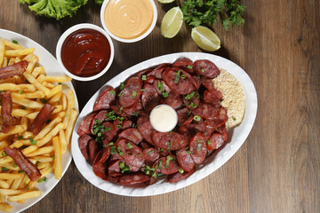 Portion of pepperoni sausage with lemon. Lettuce, green onion, ketchup and mayonnaise
