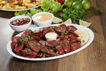 Portion of pepperoni sausage with lemon. Lettuce, green onion, ketchup and mayonnaise