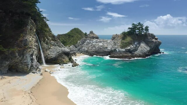 World famous waterfall landmark. Scenic waterfall on beautiful Big Sur coastline West Coast California USA. State park with picturesque teal blue lagoon. Nature environment aerial footage, drone water