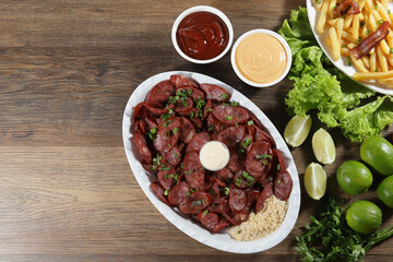 Portion of pepperoni sausage with lemon. Lettuce, green onion, ketchup and mayonnaise