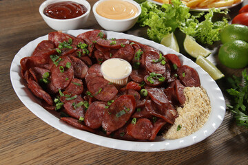 Portion of pepperoni sausage with lemon. Lettuce, green onion, ketchup and mayonnaise