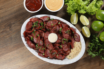 Portion of pepperoni sausage with lemon. Lettuce, green onion, ketchup and mayonnaise